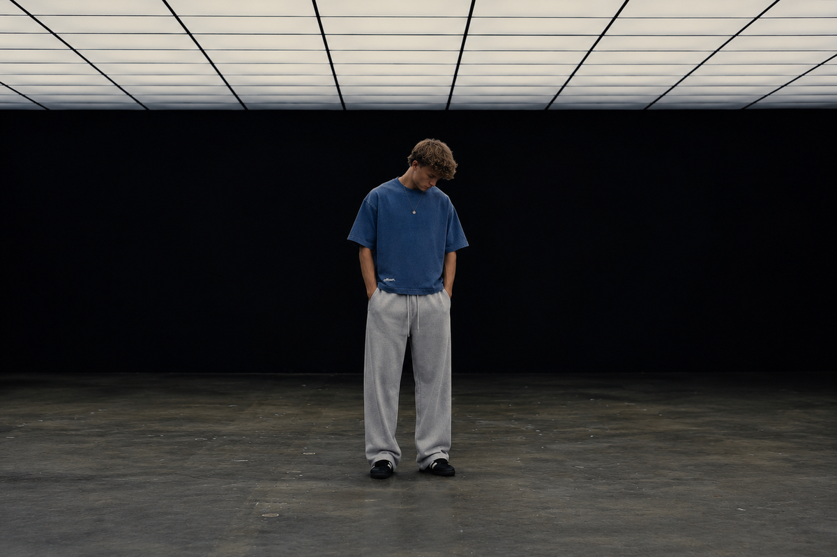 Model in a slate blue tee standing alone in an empty hall