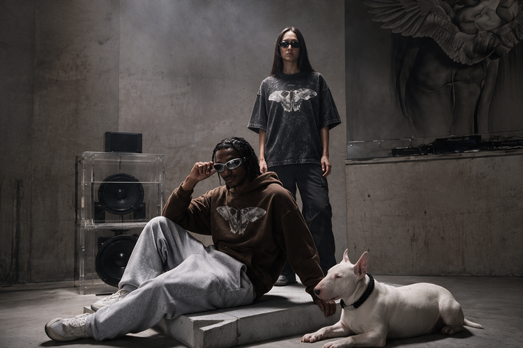 Two models in the Erebus Moth Hoodie and Nocturne Moth Tee with a white bull terrier